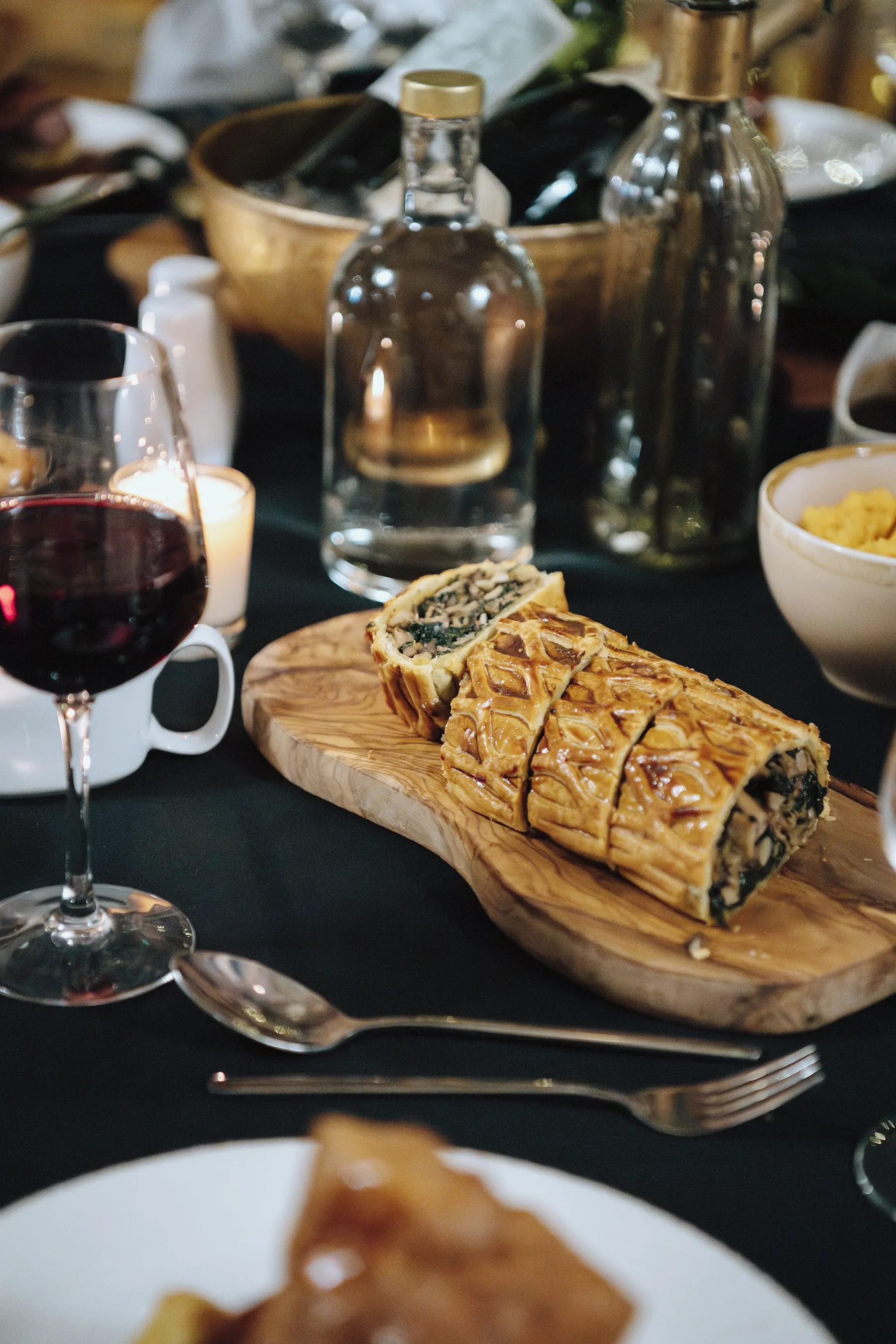 A golden pie on a board with red wine, served at an evening dinner