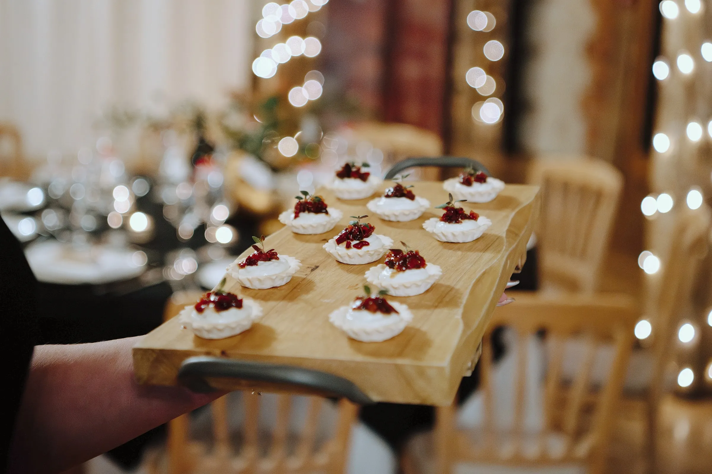 A wooden board of canapés from The Good Life, with fairy lights behind