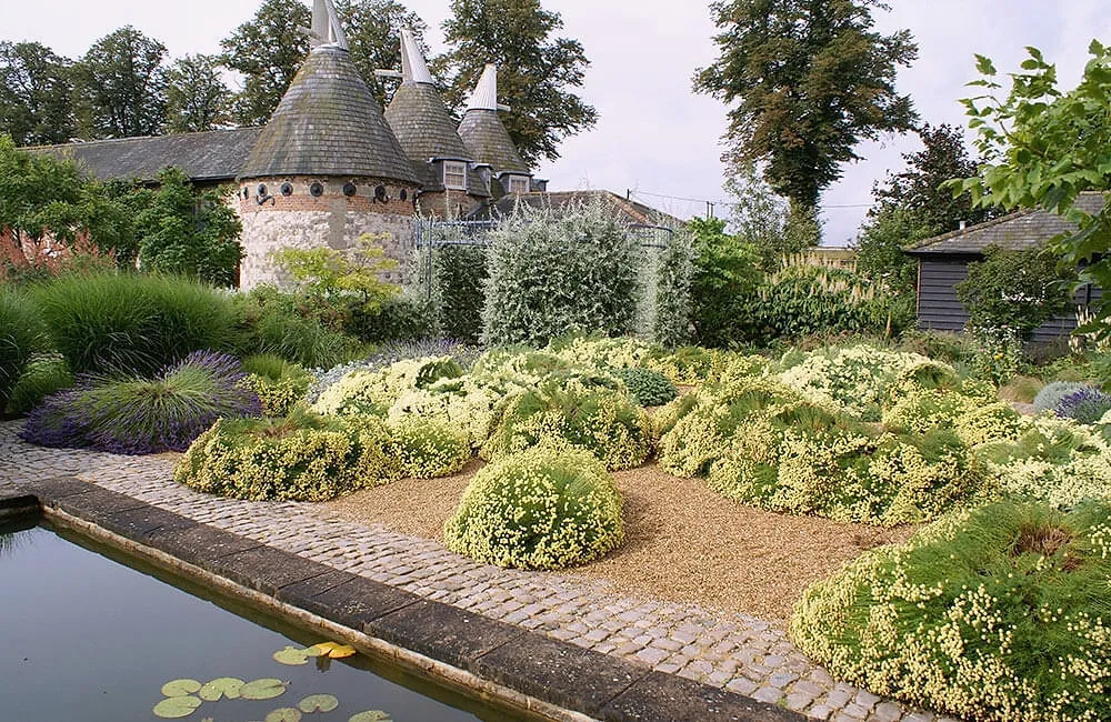 The courtyard garden's long pool edged with box domes and perennials, the oast roundel behind
