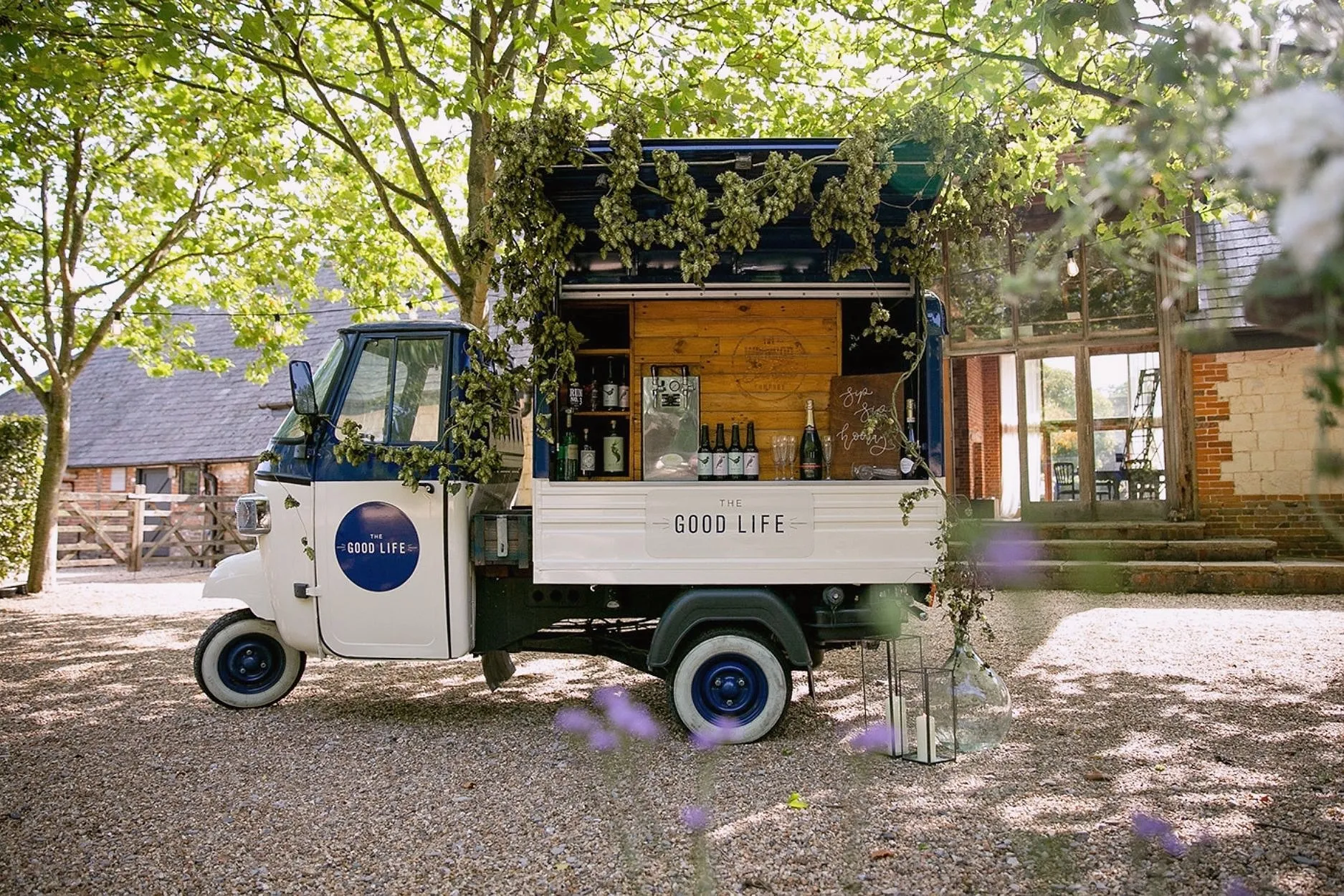 The Good Life drinks van, a small three-wheeler bar dressed with hops, in the gravel courtyard