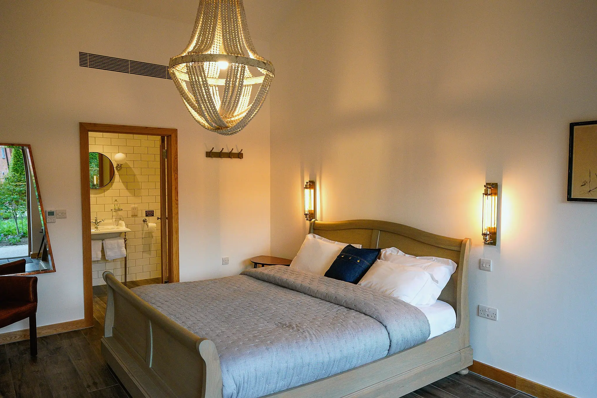 Double bedroom with a sleigh bed, beaded chandelier and an open door to a tiled en-suite