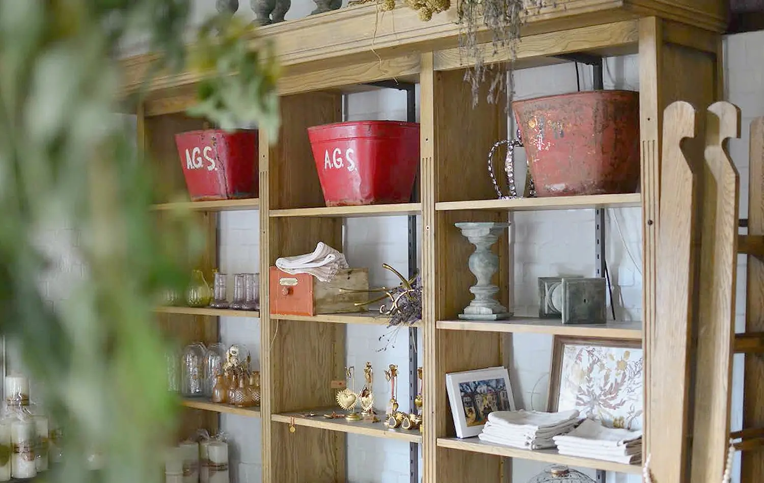 Vintage red buckets, linens and candlesticks on the shop's oak shelving
