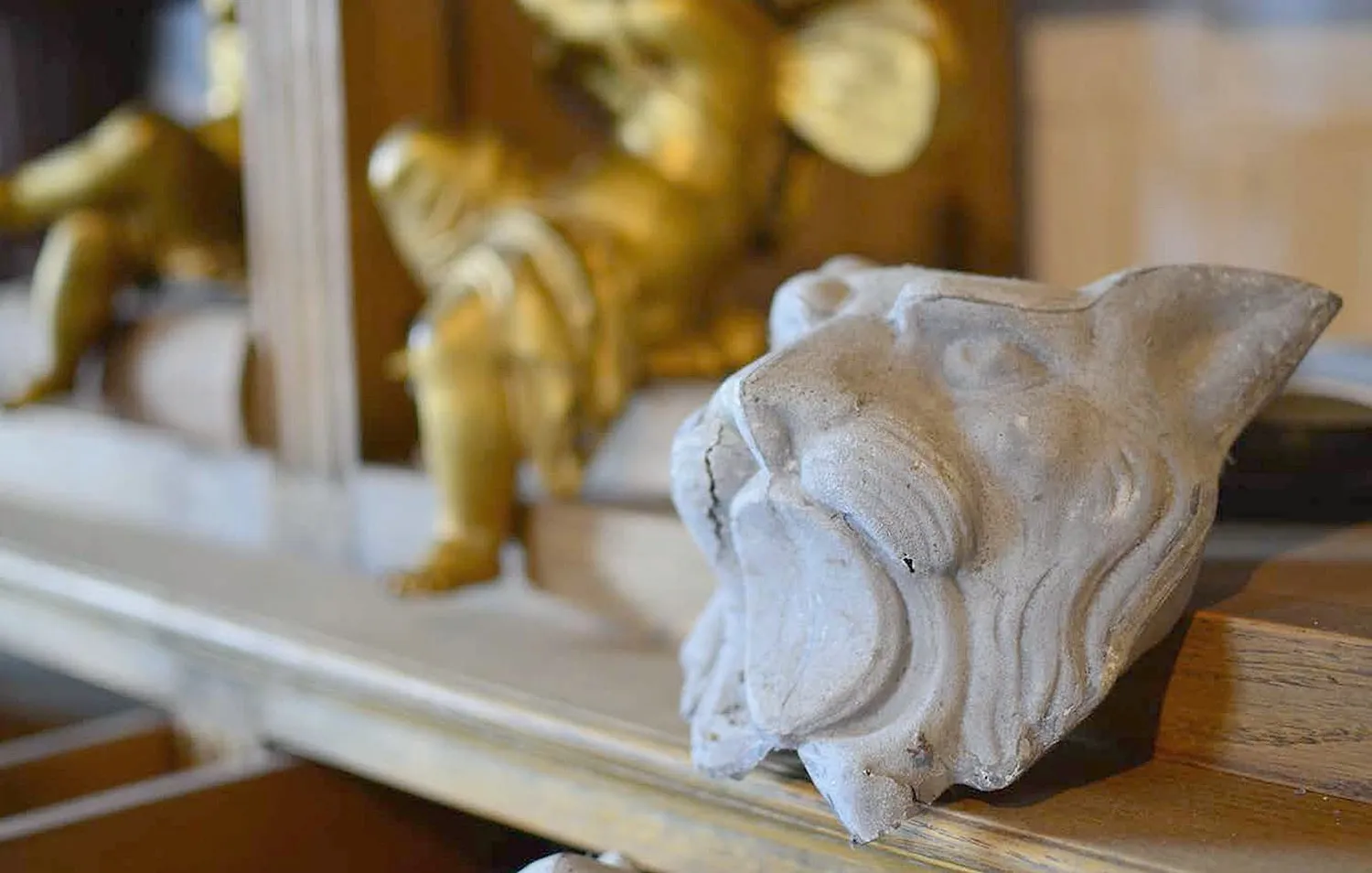A carved stone lion head beside a gilded cherub on a shop shelf