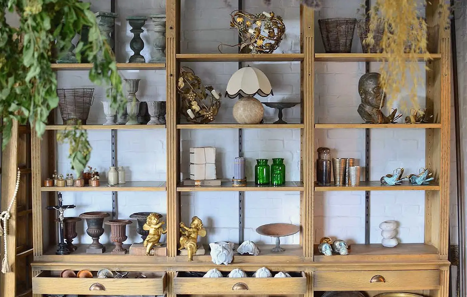 Oak shelves in the shop with urns, lamps, glassware and gilded cherubs for sale
